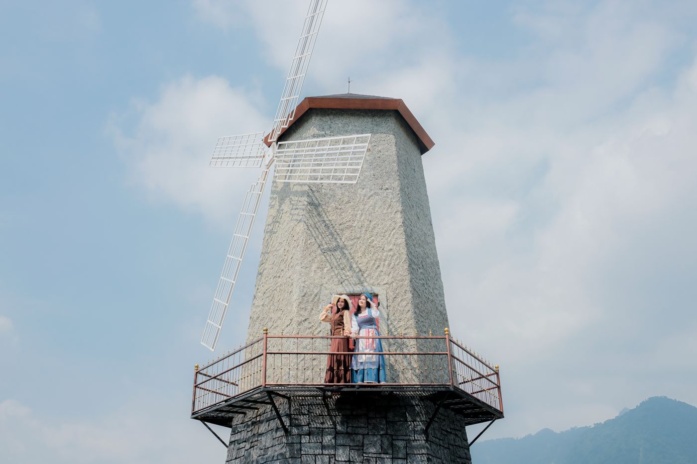 Pengunjung berfoto di menara kincir angin dengan latar pegunungan, Red Barn